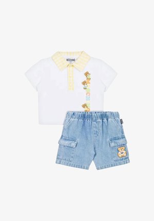 Polo bianca a maniche corte con colletto a quadretti gialli e motivo orsetto, abbinata a pantaloncini di jeans azzurri con toppa a forma di orsetto sulla tasca.