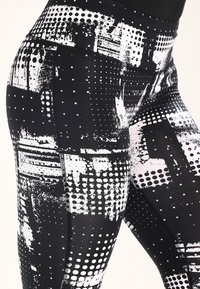 Černobílé legíny s mixem grafického vzoru obsahujícím tečky a náhodné štětcové tahy, vyrobené z elastického, hladkého materiálu.