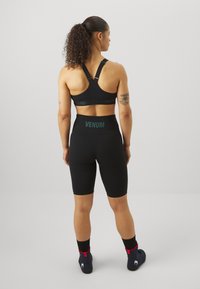 Reggiseno sportivo nero con spalline regolabili e logo; pantaloni corti neri a vita alta con logo in vita; tessuto liscio e elasticizzato.
