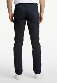 Pantaloni blu navy con vestibilità slim, cinque tasche e tasche posteriori con bottone, realizzati in un morbido tessuto di cotone misto.