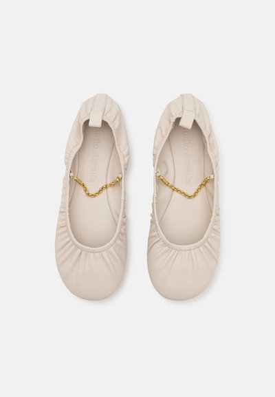 Ballerine in pelle beige con bordi arricciati, apertura elasticizzata e accentuazione in catena dorata sul collo del piede. Texture liscia e design compatto.