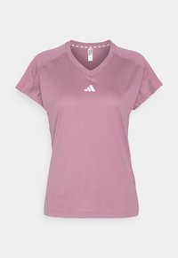 Camiseta de manga corta con escote en V en color rosa polvo, que presenta un logo blanco en el pecho y un sutil patrón triangular en el interior del cuello.