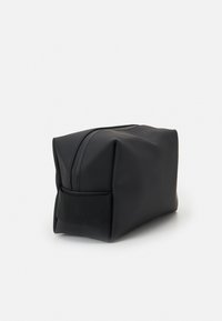 Black, rectangular toiletry bag made of soft, matte material with a zip closure and a fabric side handle for easy carrying.
