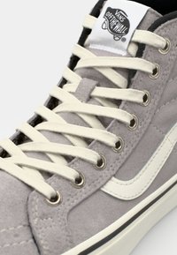 Gray suede high-top sneaker with white laces, metal eyelets, branded tongue tag, and distinctive white side stripe detail.