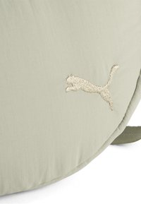 Beige stoftas med en struktureret overflade; har et broderet guld Puma-logo. Designet er rundt med en skulderrem.