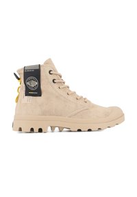 Botas altas beige hechas de lona texturizada con ojales negros, suela de goma y una etiqueta de logo en el costado con una tira amarilla.