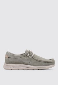 Zapato de ante gris claro con punta redonda, costura decorativa, perforaciones laterales y un suave acento beige en el talón. Suela de goma flexible.