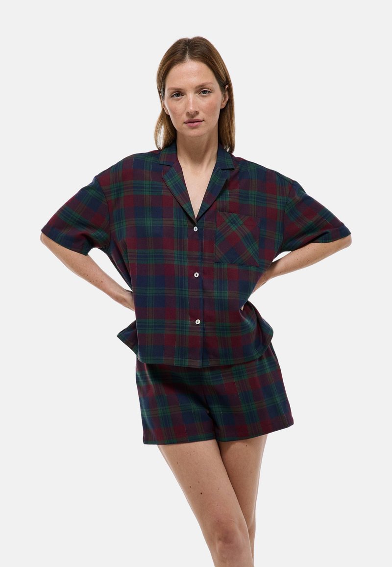 Ensemble de vêtements d'intérieur à carreaux en vert foncé et bordeaux. Chemise à manches courtes avec boutons et poche, assortie à un short, en tissu lisse.