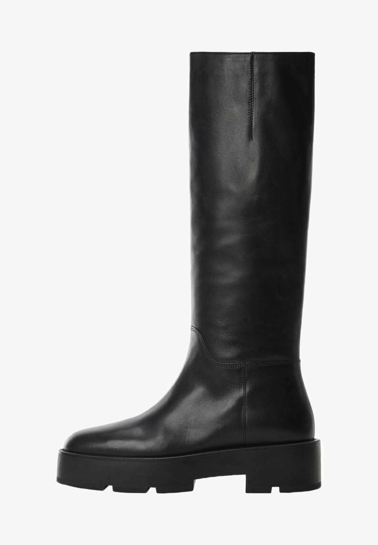 Botte noire en cuir montant jusqu'aux genoux avec semelle crantée épaisse et bout arrondi, conçue pour la mode et la durabilité.