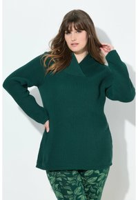 Dunkelgrüner gerippter Pullover mit Schalkragen und langen Ärmeln. Kombiniert mit grünen Leggings mit einem Blattmuster. Weiche Textur, lockere Passform.