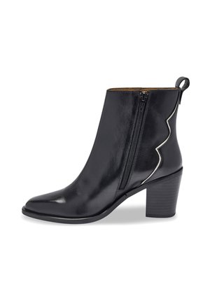 Bota de cuero negro de tobillo con punta afilada, cremallera lateral y un acento plateado curvado. Presenta un tacón apilado y una textura suave.