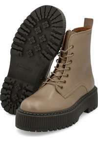 Botas de tobillo de cuero beige con punta redonda, diseño de cordones con ojales y suela de goma negra gruesa con relieve profundo para mayor tracción.