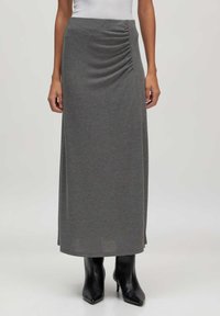 Grijze maxi-rok van zachte, gladde stof met zijkant ruchingdetails. Gecombineerd met zwarte hoge laarzen. Heeft een rechte, vloeiende silhouet.