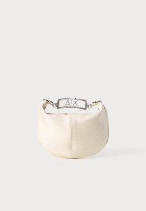 Metalická krémová kabelka s zakriveným tvarom, vybavená strieborným logom a hladkým textilným povrchom.