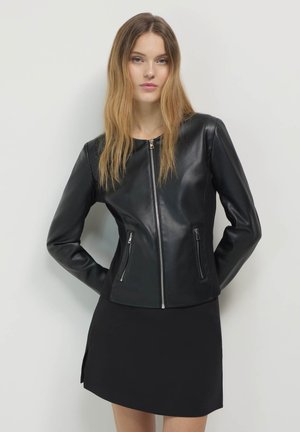 Giubbotto in pelle nera con un design aderente, maniche lunghe e due tasche frontali con zip. Texture liscia e scollo rotondo.