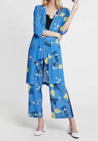 Modrý kimono kabátek s květinovým vzorem a žlutými a černými akcenty, doplněný odpovídajícími širokými kalhotami. Lehká látka, tříčtvrteční rukávy.