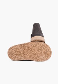 Scarpa slip-on in suede nera con suola in gomma testurizzata, caratterizzata da un bordo marrone e un motivo di presa distintivo per la trazione.