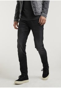 Jeans z ciemnego denimu o slim fit, w połączeniu z czarną koszulką i szaro-denimową kurtką. W zestawie czarne zamszowe sneakersy z białą podeszwą.