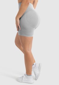 Grijze hooggezette sportshorts met een textuur en een aansluitend ontwerp. Gecombineerd met witte sportschoenen met zwarte accenten.