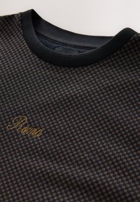 Black and brown checker-patterned textile shirt with a round neckline and textured collar. Features "Roma" embroidered in gold.