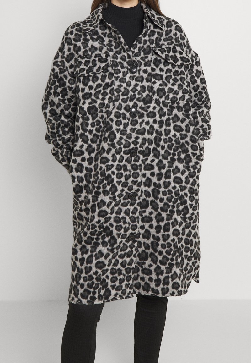 Oversized Mantel mit Leopardenmuster in Grau und Schwarz, ausgestattet mit einem Knopfverschluss, zwei Brusttaschen und einem Kragen, aus einem weichen, strukturierten Stoff gefertigt.