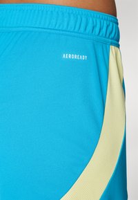 AEROREADY sportiniai šortai ryškiai mėlynos spalvos, su kreminės spalvos šonine juosta su tekstūruotu raštu ir elastingu liemeniu.