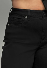 Zwarte denim jeans met een gladde textuur, een klassiek vijf-pocket ontwerp en metalen accenten op de taille en zakken.