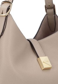 Beige leather shoulder bag with a textured surface, featuring a gold-tone geometric accent and a contrast leather strap.
