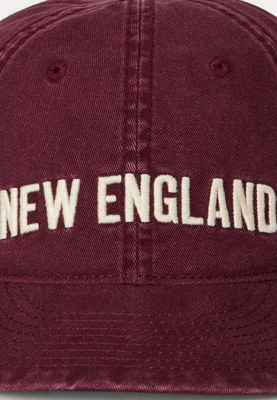 Burgundy baseball cap with embroidered "NEW ENGLAND" in white, featuring a curved brim and subtle textured fabric.