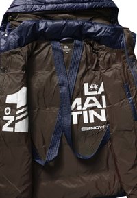 Navy modrá padded bunda s hnědým interiérem, s velkým bílým textem a logem. Obsahuje prošívané popruhy a patentky. Velikost M.