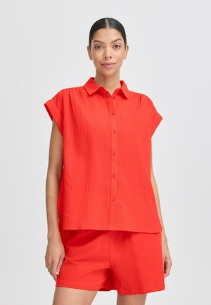 Camisa roja de manga corta y botones con tejido texturizado, combinada con pantalones cortos rojos a juego. Diseño sencillo, corte relajado, sin patrones ni acentos visibles.