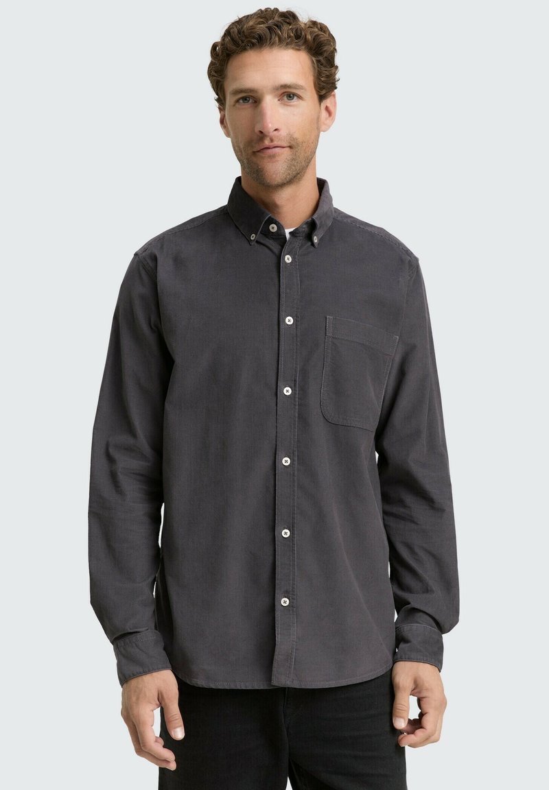 Camisa de manga larga y botones en corduroy gris oscuro con un solo bolsillo en el pecho y botones blancos. Textura suave y diseño de cuello estándar.