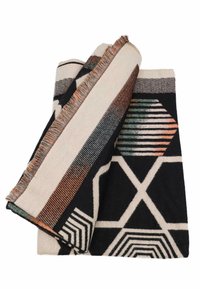 Coperta tessuta con motivi geometrici in nero, crema e accenti di verde e arancione. I bordi frangiati aggiungono un dettaglio di texture.