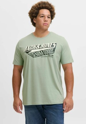 Zeleni pamučni T-shirt s hrabrim crnim i kremgrafičkim otisakom na kojem piše "JACK & JONES DENIM GOODS" na prednjoj strani. Okrugli izrez, kratki rukavi.