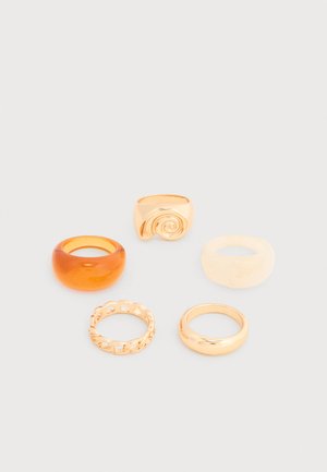 Vijf verschillende ringen op een witte ondergrond, waaronder gouden ringen, een chunky ring in amberkleur, een chunky ring in crème en een gouden ring met een swirl-ontwerp.