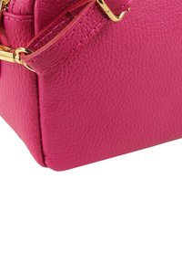 Rosa Ledertasche mit strukturierter Oberfläche, ausgestattet mit einem goldfarbenen Verschluss und Riemen. Quadratische Form mit einfarbigem Design und sichtbaren Nähten.