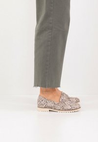 Μοκασίνια με σχέδιο δέρματος φιδιού σε μπεζ και καφέ χρώμα με υφή, διαθέτουν χαμηλή ανοιχτόχρωμη σόλα και σχεδιασμό slip-on.