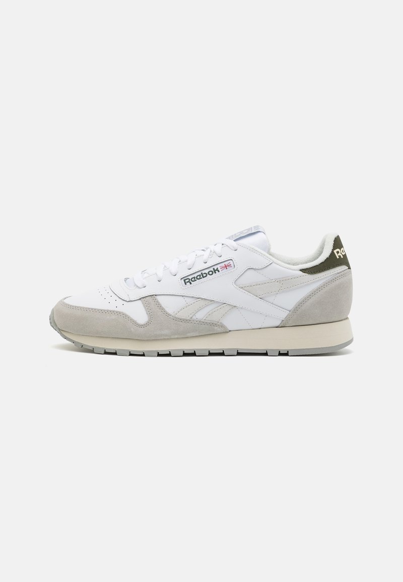 Baskets Reebok blanches et gris clair avec accents en daim, lacets à l'avant et logo sur le côté et le talon, présentées de profil sur un fond uni.