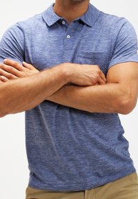 Blå heathered polo skjorta med krage, två knappar och en ficka på vänster bröst, tillverkad av ett mjukt, något texturerat tyg.