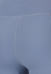 Light blue activewear shorts made of smooth fabric, featuring flat seams and an elastic waistband with subtle branding on the back.