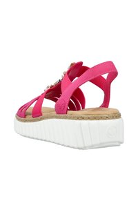 Roze sandalen met bandjes, een kurken voetbed, een witte platformzool en decoratieve accenten op de bandjes. De achteraanzicht benadrukt de hakhoogte.