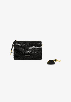 Pochette tissée noire avec tirette de fermeture éclair dorée et bandoulière en cuir noir amovible avec fermoirs dorés, isolée sur fond blanc.