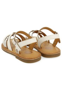 Sandalias de cuero blancas con múltiples correas cruzadas, hebilla ajustable, plantilla interna color marrón claro y suela de goma marrón claro.