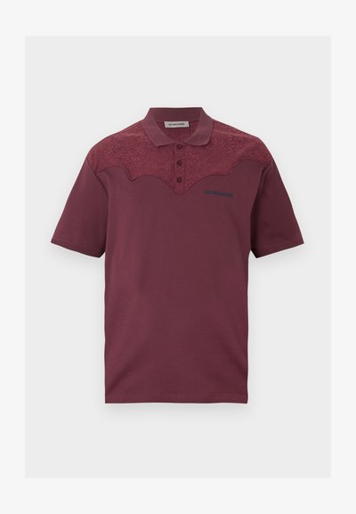 Κοντομάνικο πουκάμισο πόλο μπορντό με λουλουδάτο δαντελένιο κόψιμο, τρία κουμπιά και μικρό λογότυπο «Les Benjamins» στο στήθος.