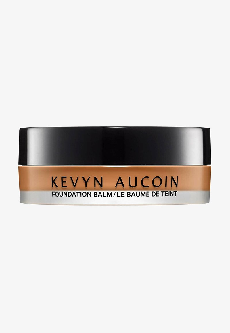 Balsamo della Fondazione Kevyn Aucoin in un barattolo rotondo con un coperchio nero. Il contenitore ha una base beige con scritte argentate. Texture liscia e cremosa.