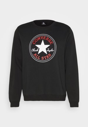 Zwarte trainingssweater met lange mouwen, voorzien van een wit sterlogo en rode tekst "Converse All Star" die "Chuck Taylor" in witte cursief op de voorkant omringt.