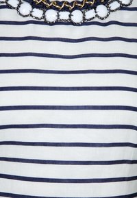 Paski w poziome niebieskie i białe, z teksturowanym kołnierzykiem ozdobionym białymi koralikami i złotymi łańcuszkami.