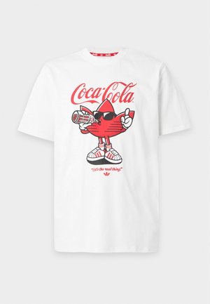 Weißes T-Shirt mit rotem Coca-Cola-Logo und einer roten Cartoon-Adidas-Trefoil-Figur, die Sonnenbrille und Turnschuhe trägt, Limonade trinkt und nach oben zeigt.