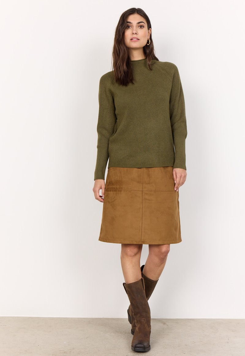 Olivgrüner gerippter Strickpullover und brauer Wildlederrock bis zum Knie, kombiniert mit braunen Lederstiefeln. Einfaches Design mit klaren Linien.