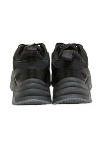 Par sorte atletiksneakers set bagfra med tykke såler, mesh og læder overdel samt trækstropper ved hælkappen.